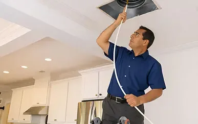 Duke's technician cleaning a ceiling air duct inside a home